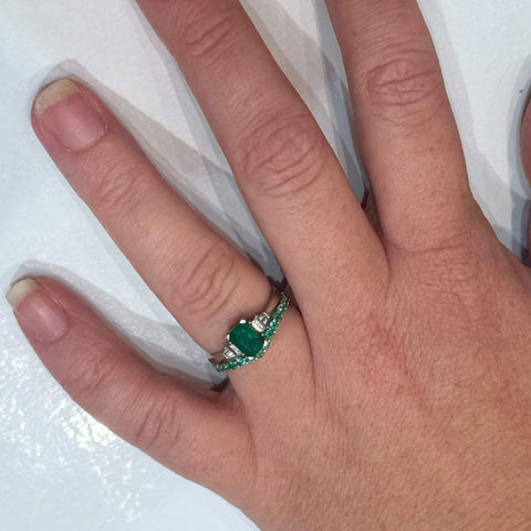 Custom white gold emerald band worn on hand of customer