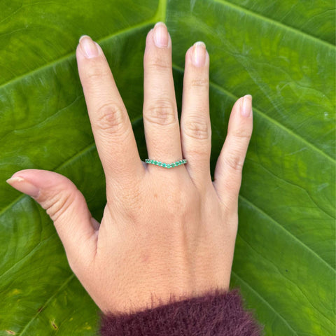 V-shaped emerald wedding band contour design in hand