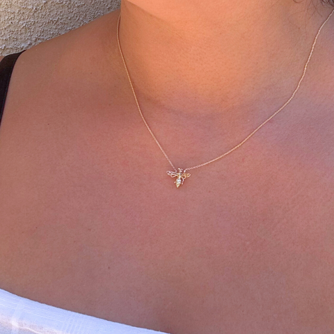 Yellow gold bee necklace worn on skin – minimalist styling
