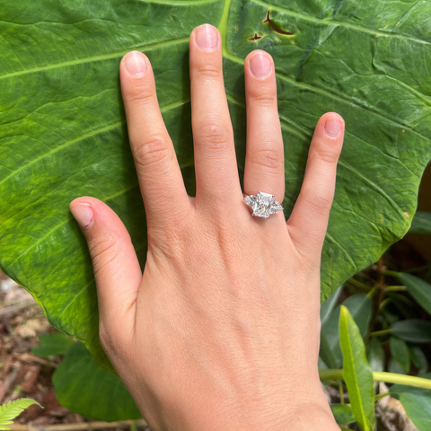 Platinum radiant trilogy engagement ring worn outdoors, feminine natural-light style