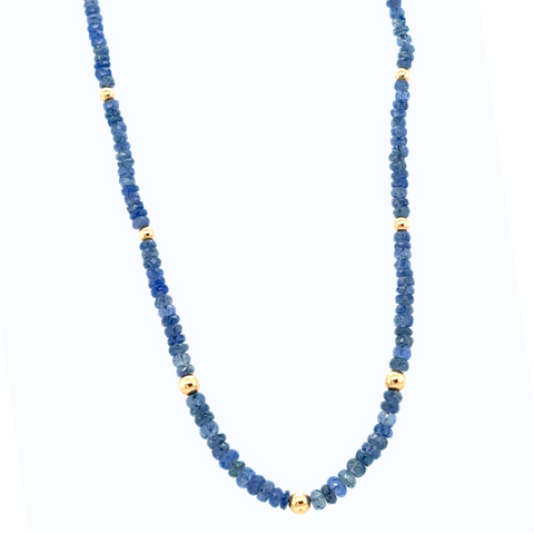 Natural sapphire gemstone strand with gold rondels laid out on neutral surface