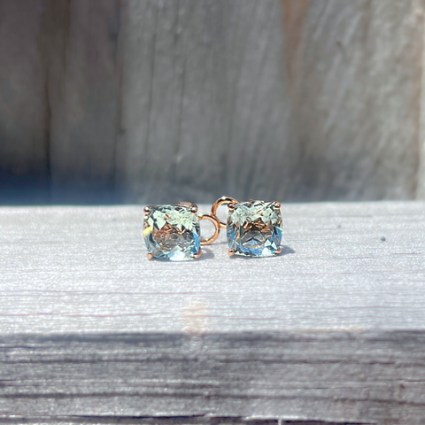 Square-cut green amethyst earrings in yellow gold displayed on neutral textured surface