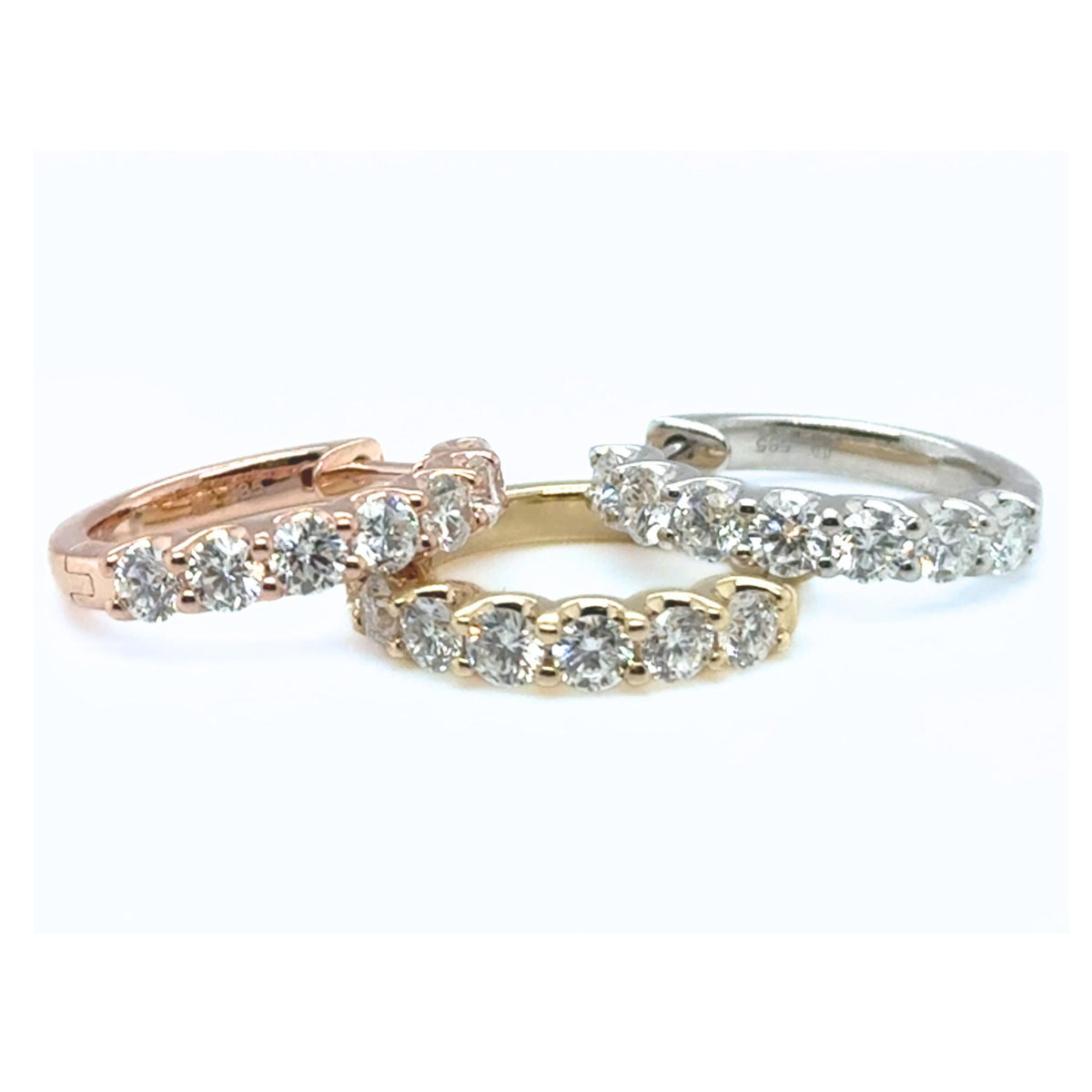 Collection of mixed-gold diamond huggie earrings showcased with round lab grown diamonds.