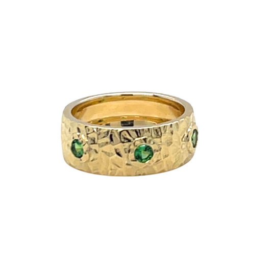 Gold ring with green gemstones on a white background