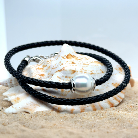 South Sea pearl double wrap leather bracelet with silver accents displayed on natural surface.