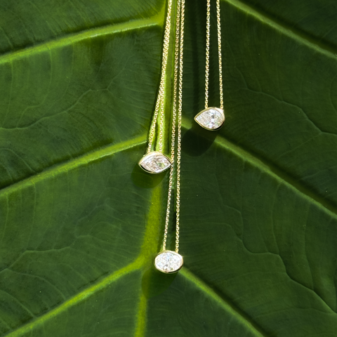 Pear Aroha gemstone slider necklaces displayed on green leaf