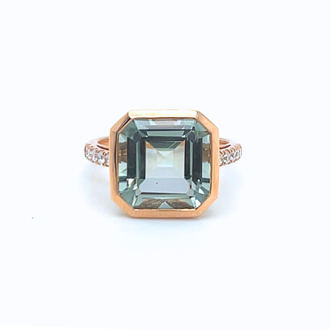 Rose gold ring with a large green gemstone on a white background