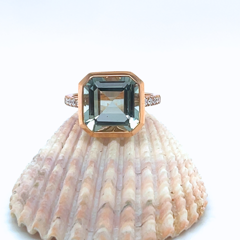 Ring with a large green gemstone on a shell against a white background
