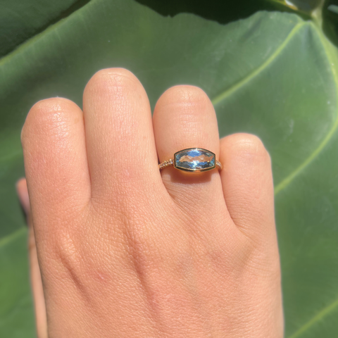 Blue topaz diamond ring worn on hand, feminine natural-light coastal style