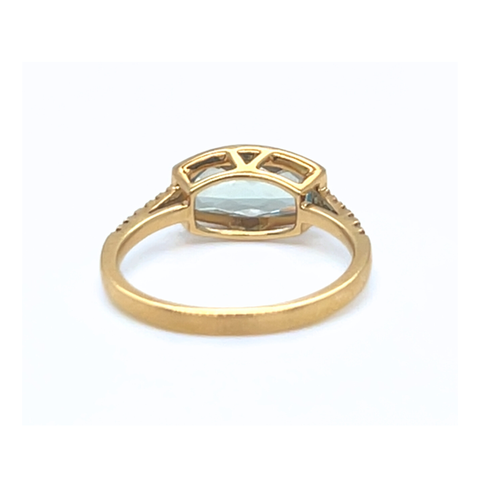 Elongated cushion-cut blue topaz ring in yellow gold displayed with soft light