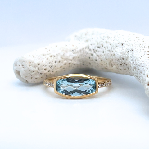 Blue topaz ring in yellow gold worn outdoors, soft coastal-inspired jewellery photography