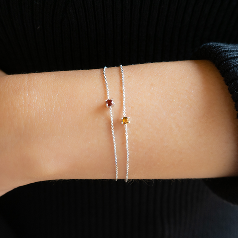 Delicate 9kt gold birthstone bracelet worn on wrist with small round gemstone.
