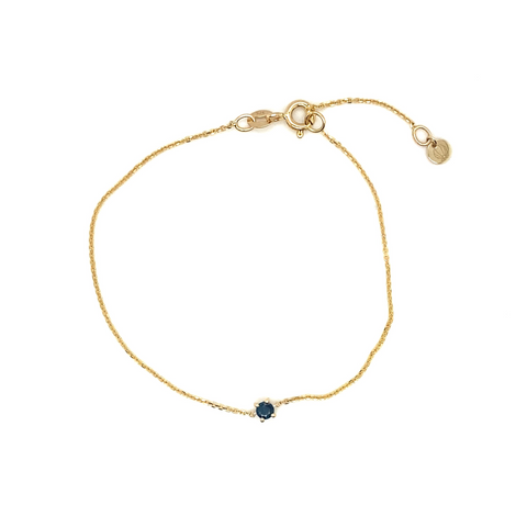 “Close-up of 9kt gold birthstone bracelet featuring round gemstone in minimalist setting.