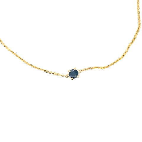 Gold birthstone bracelet worn on wrist with delicate chain and gemstone accent.